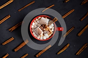 Red ceramic cups of hot cocoa with marshmallows on top of black rustic background