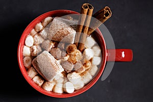 Red ceramic cups of hot cocoa with marshmallows on top of black rustic background