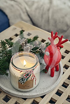 Red ceramic deer and candle in jar with fir tree branches