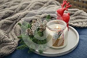 Red ceramic deer and candle in jar with fir tree branches