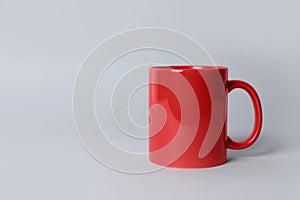 Red ceramic mug on light grey background. Space for text