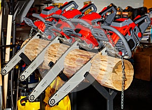 Red chainsaws are stuck in a log. Professional garden tool concept