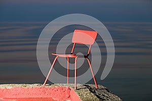 Red chair on a lagoon background. Lithuania, Nida