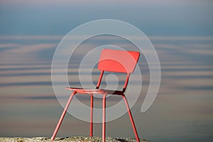 Red chair on a lagoon background. Lithuania, Nida