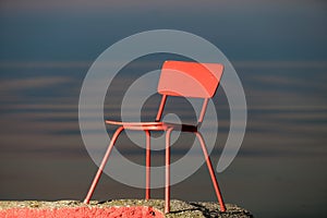 Red chair on a lagoon background. Lithuania, Nida