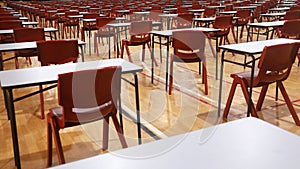 Red chairs and exam tables or desks neatly arranged in rows in a college or school hall
