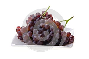 Red champagne grapes on white plate