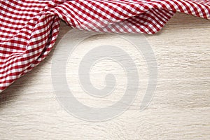 Red checered cloth on wooden table top view. Picnic towel on light wood texture background empty advertisement space