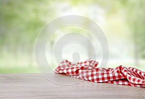 Red checkered cloth on wooden table empty space. Picnic towel natural background food display