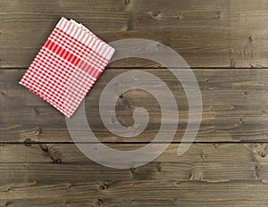 Red checkered dishcloth on brown rustic wooden plank table flat lay top view from above