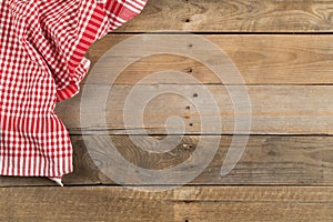 Red checkered dishcloth on brown rustic wooden plank table flat lay top view from above