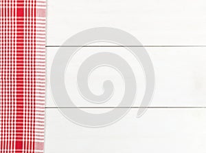 Red checkered dishcloth on white wooden plank table flat lay top view from above