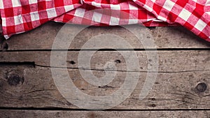 Red checkered kitchen towel on vintage wooden background.