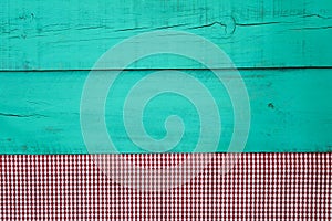 Red checkered tablecloth bodrer on antique green wooden background