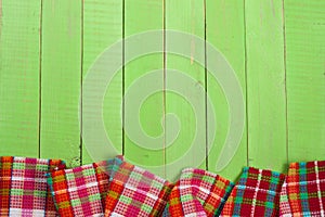 Red checkered tablecloth on a green wooden table with copy space for your text. Top view