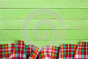 Red checkered tablecloth on a green wooden table with copy space for your text. Top view