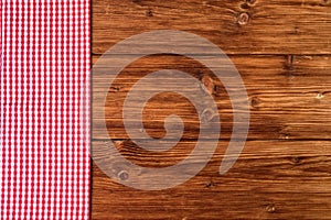 Red checkered tablecloth on old wooden background Top view, text space