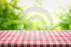Red checkered tablecloth texture top view with abstract green bokeh