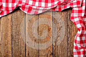 Red checkered tablecloth top and right frame on vintage wooden table background - view from above