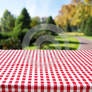 Red Checkered tablecloth top view with blur abstract green bokeh design garden. Selective focus. Copy space. Place for food