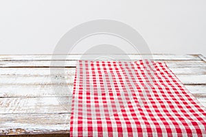 Red checkered tablecloth on a wooden kitchen table, copy space