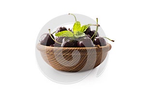 Red cherries in bowl isolated on white background. Ripe cherries and mint leaves close-up. Sweet and juicy berry with copy space f