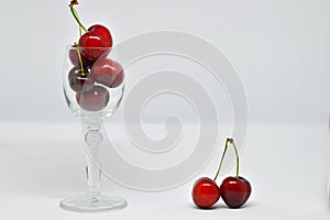 Red cherries in glass cup on white background
