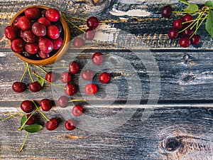 Red cherries lie in a wooden bowl.