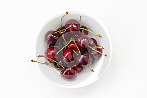 Red cherries in a white bowl on the white background, isolated.