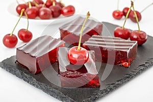Red cherry jelly dessert with gelatin. Fruit jell squares on black board