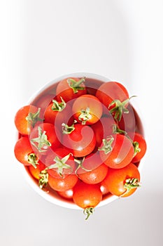 Red cherry tomato in  ceramic bowl on white background