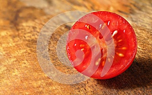 Red cherry tomato cut in half on wooden kitchen board. Closeup macro detail