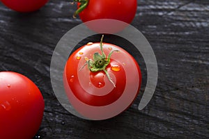 Red cherry tomatoes on black rustic wood background