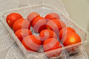Red cherry tomatoes in plastic packaging on table