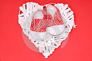 Red children`s shoes with white polka dots on a decorative white heart