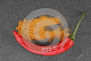 Red chili pepper and ground red pepper on black stone table