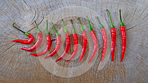 Red chili peppers arranged in a row on a wooden table.