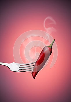 Red chili peppers on a fork with smoke on a red gradient background