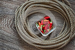 Red chili peppers, fresh vegetables in a white plate in the center of a rope circle