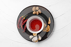 Red chili peppers and other spices on white textured background, top view