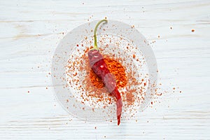 Red chili peppers on a wood table with chili powder from above