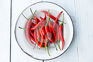 Red chilli pepper in old plate on white table