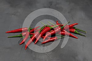 Red chilli peppers on dark gray stone background.