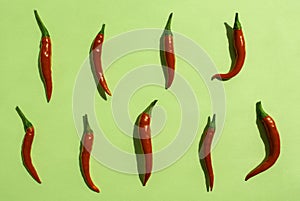 Red chilli peppers pattern on green background. Top view. Hot pepper flat lay