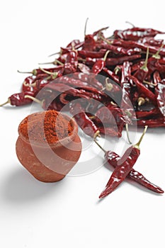 Red chilli powder with dried red chillies. in earthen bowl