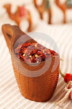 Red chillies paper flakes in curved wooden bowl