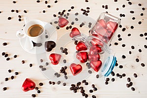 Red chocolate hearts in a glass jar and a cup of espresso coffee
