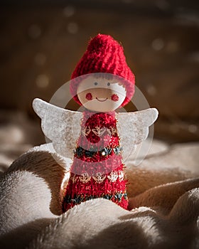 Red Christmas angel statuette on a white blanket and bokeh background