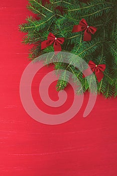 Red Christmas background with green tree bows on wooden background