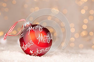 Red christmas ball with text Merry Christmas and bokeh of yellow christmaslights